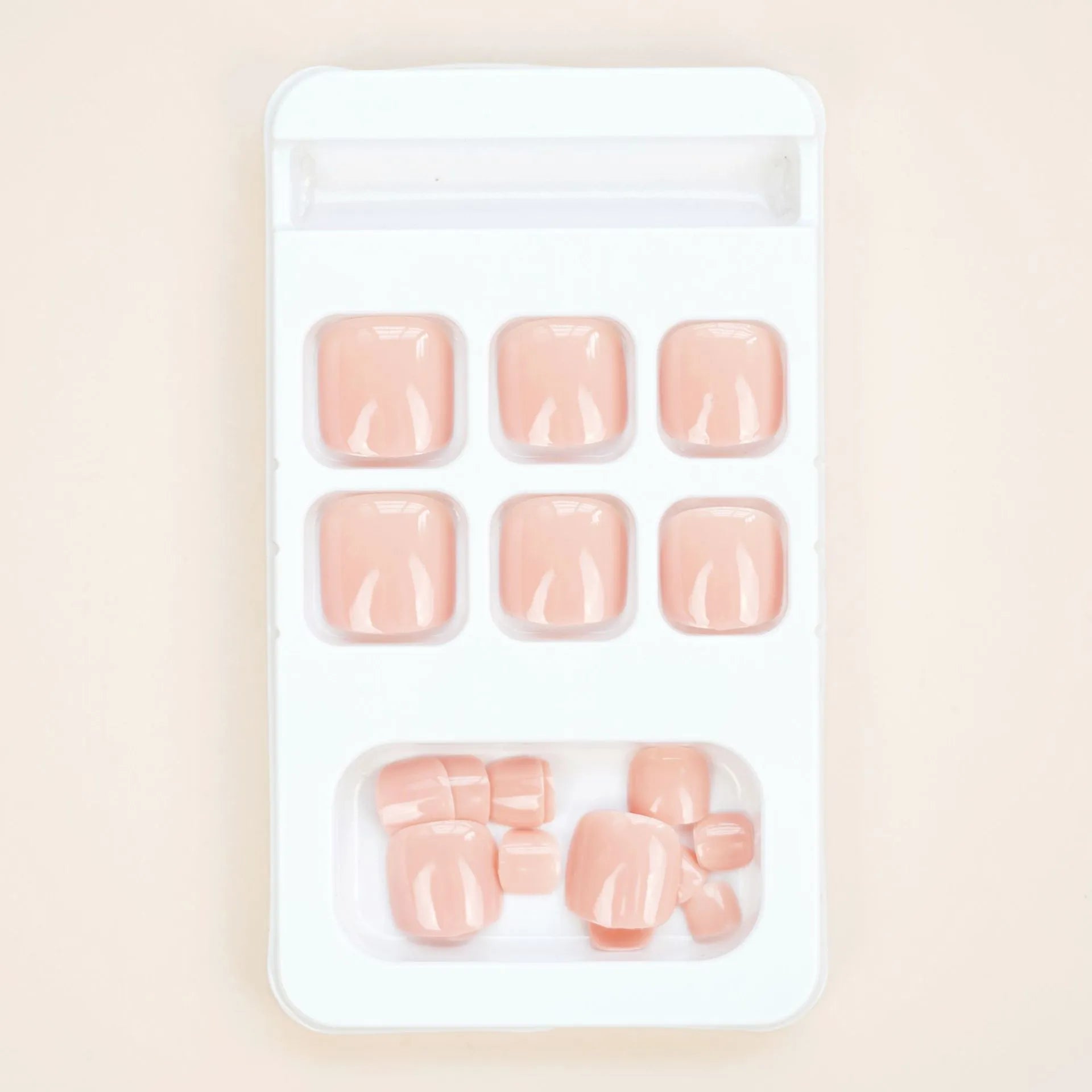 Plastic toenail stickers in skin colour with adhesive glue bottle on white background