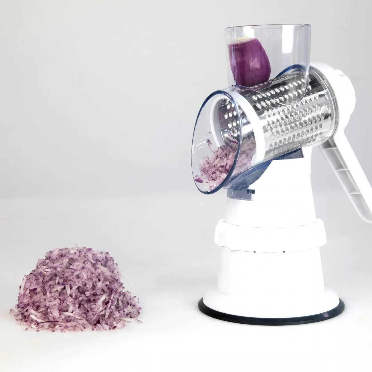 White 3-in-1 manual vegetable slicer and grater with suction feet on a kitchen counter.