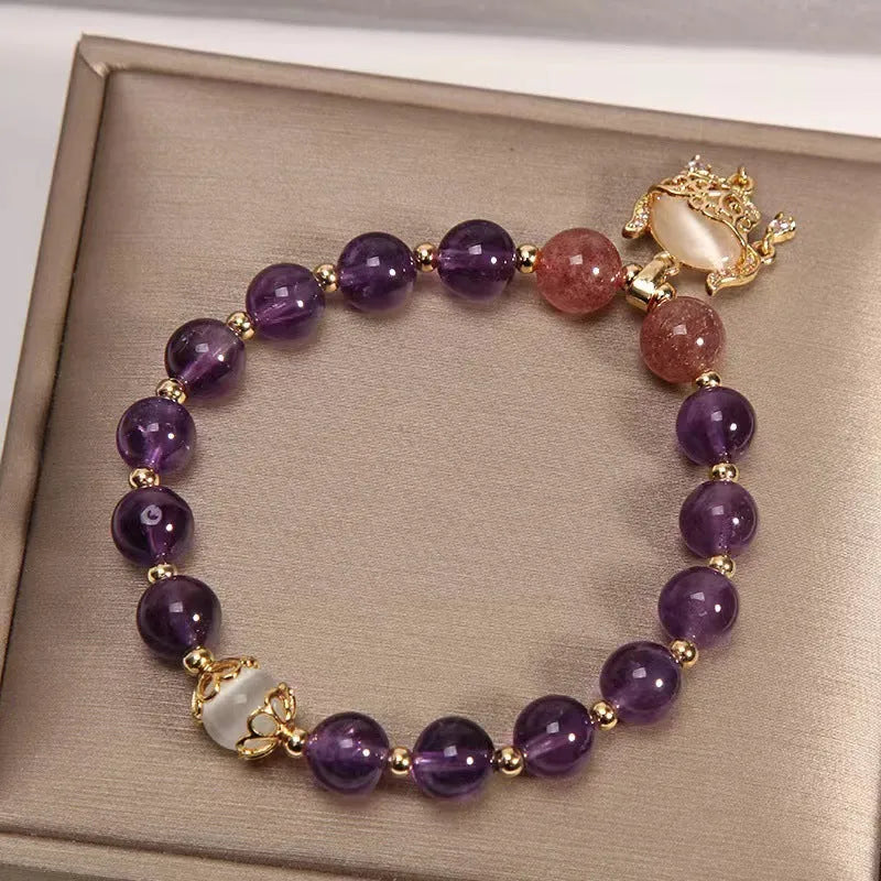 Close-up of a handmade copper bracelet for women with a drop-shaped longevity lock charm, Ruyi element, amethyst stones, and gold accents.