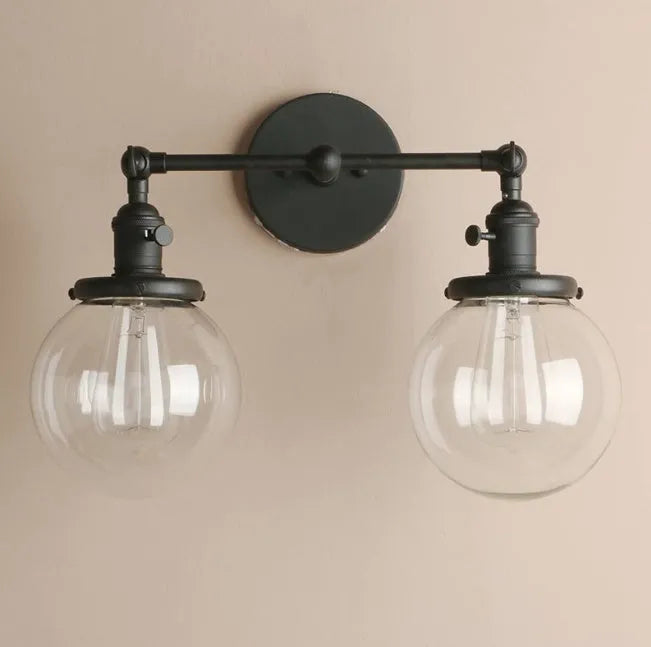Double headed black iron wall lamp with spherical glass shades on a wall