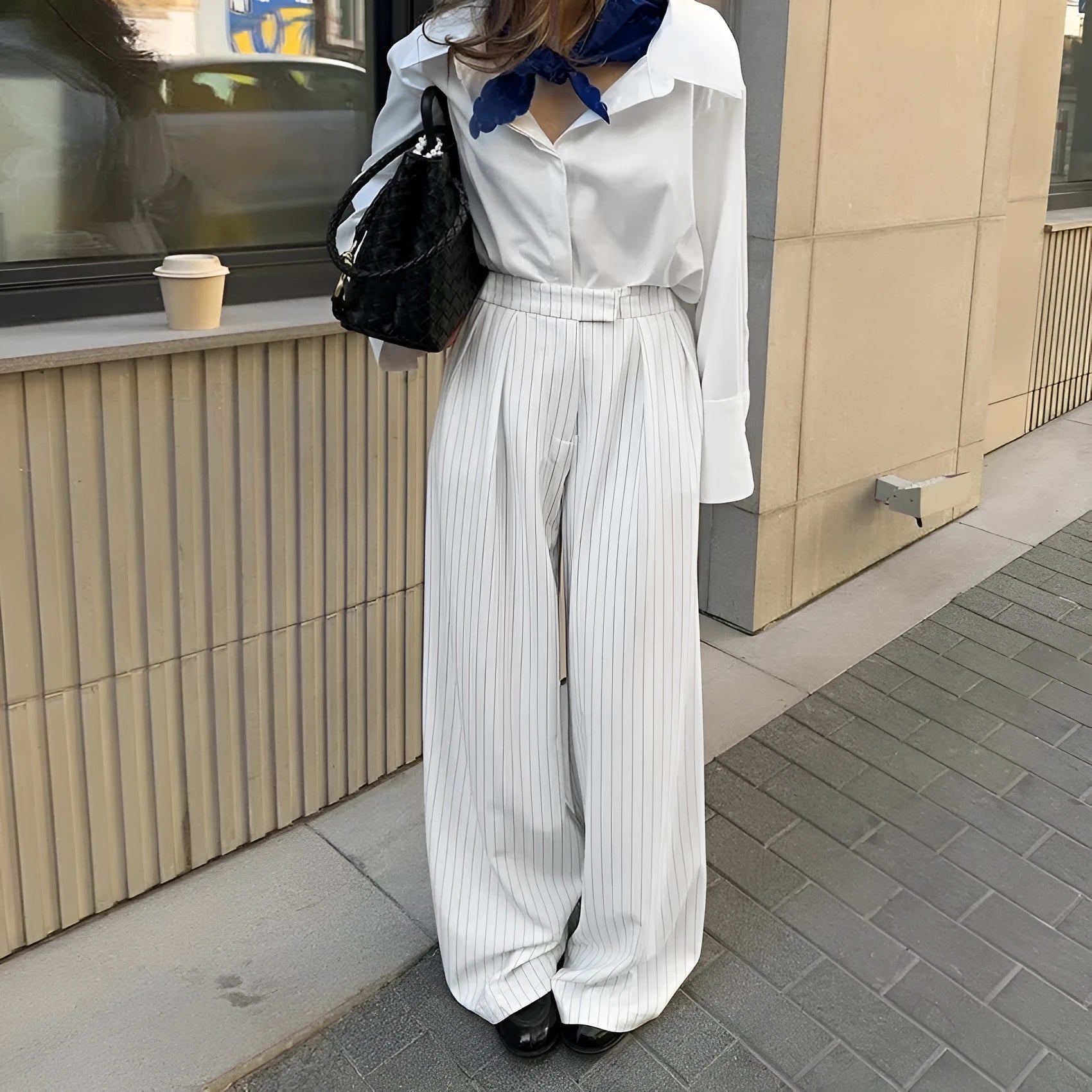 White striped loose-fit wide-leg trousers with a front zipper closure on a model.