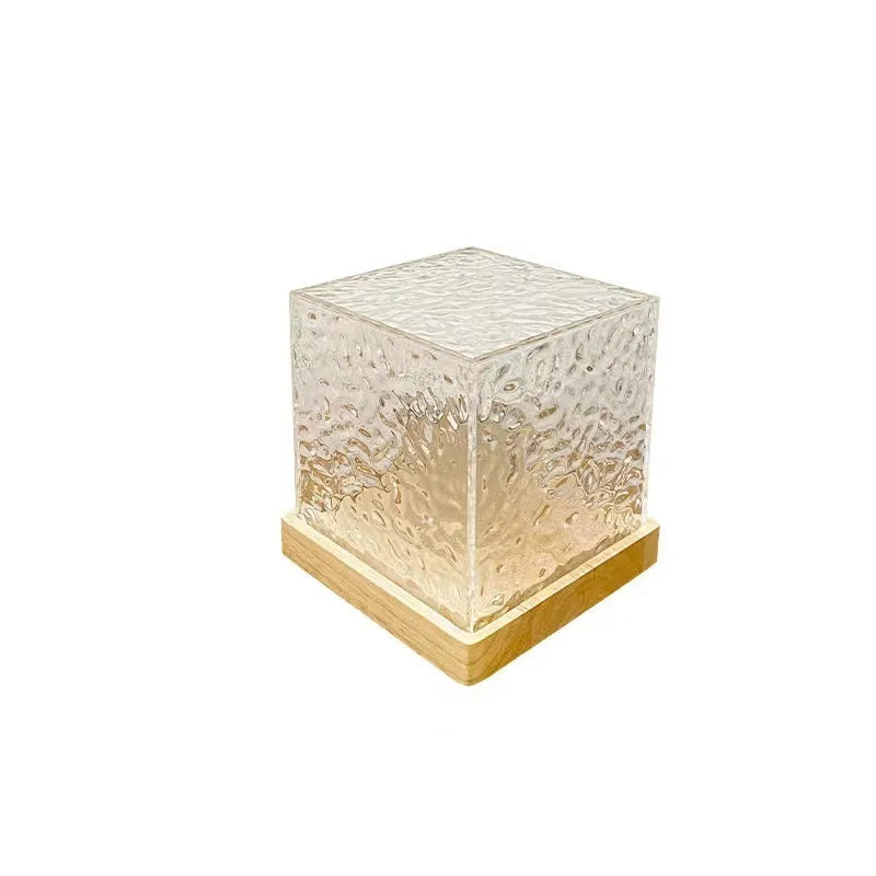 Square crystal LED table lamp projecting blue water ripple light patterns on a wall.