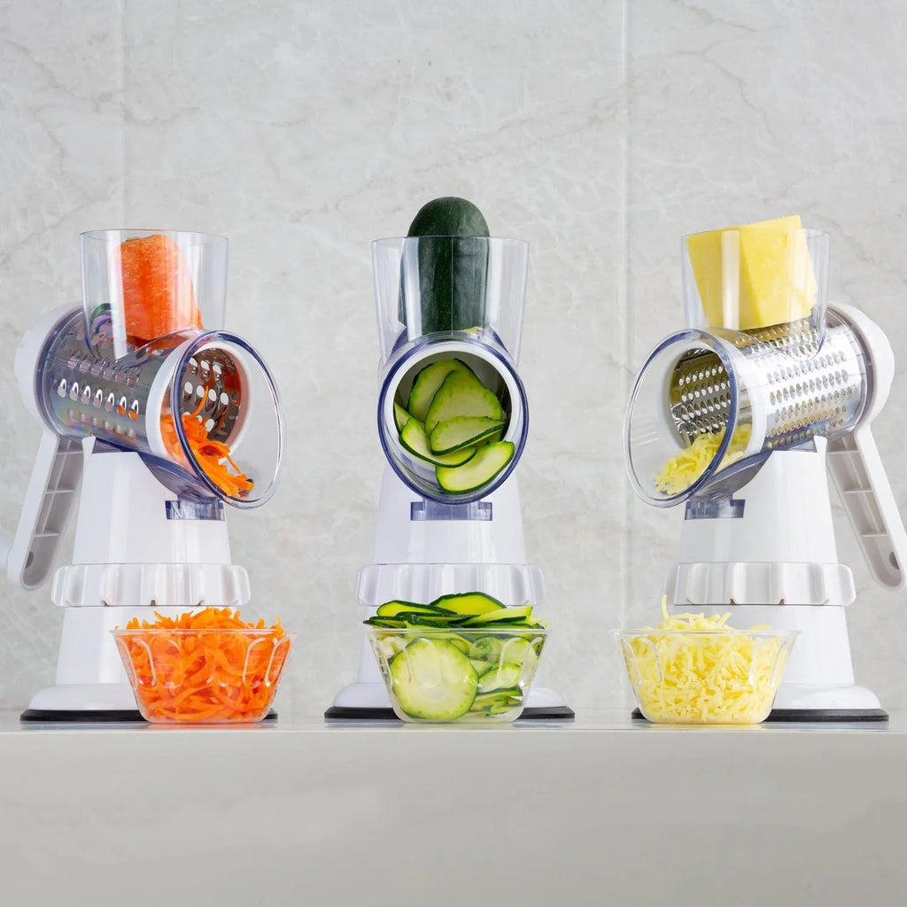 White 3-in-1 manual vegetable slicer and grater with suction feet on a kitchen counter.