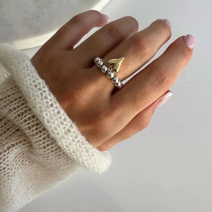 Handmade elastic love ring with geometric beaded string design and heart charm on adjustable band