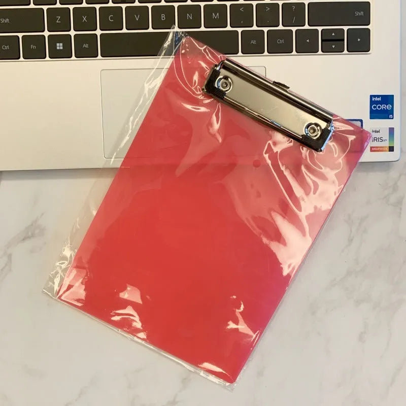 Transparent A4 clipboard with metal clip, shown in blue colour on a wooden desk.