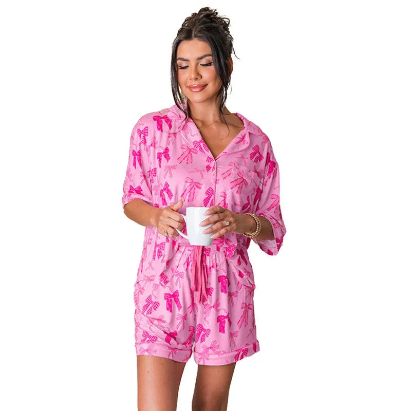 Pink women's pyjama set with bow print, featuring a top and trousers.