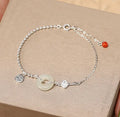 Women's silver bracelet with a geometric Hetian jade peace buckle charm on a chain.