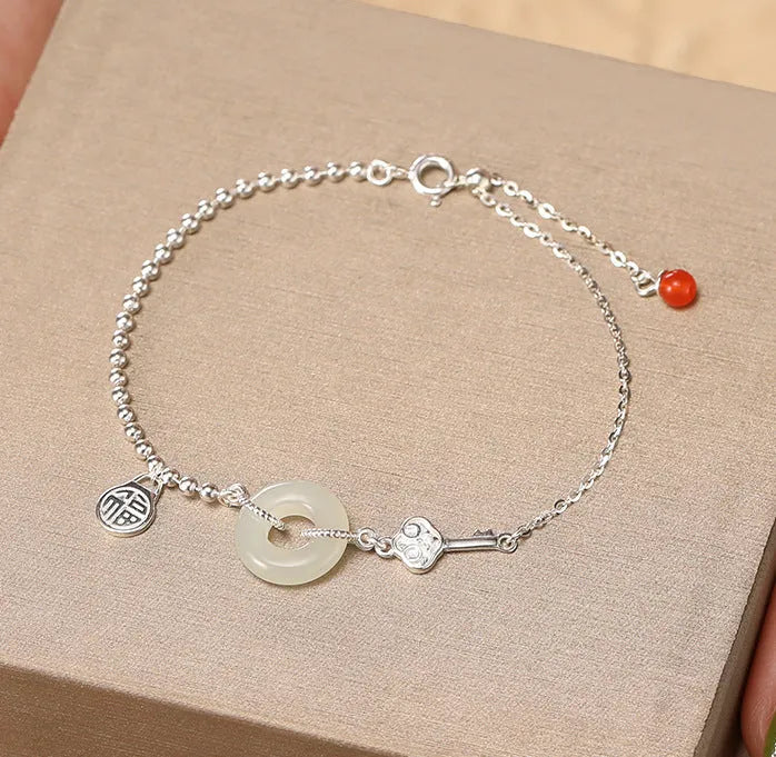 Women's silver bracelet with a geometric Hetian jade peace buckle charm on a chain.