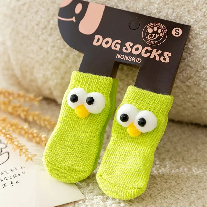 Dog wearing green non-slip socks with cartoon big eyes pattern on wooden floor