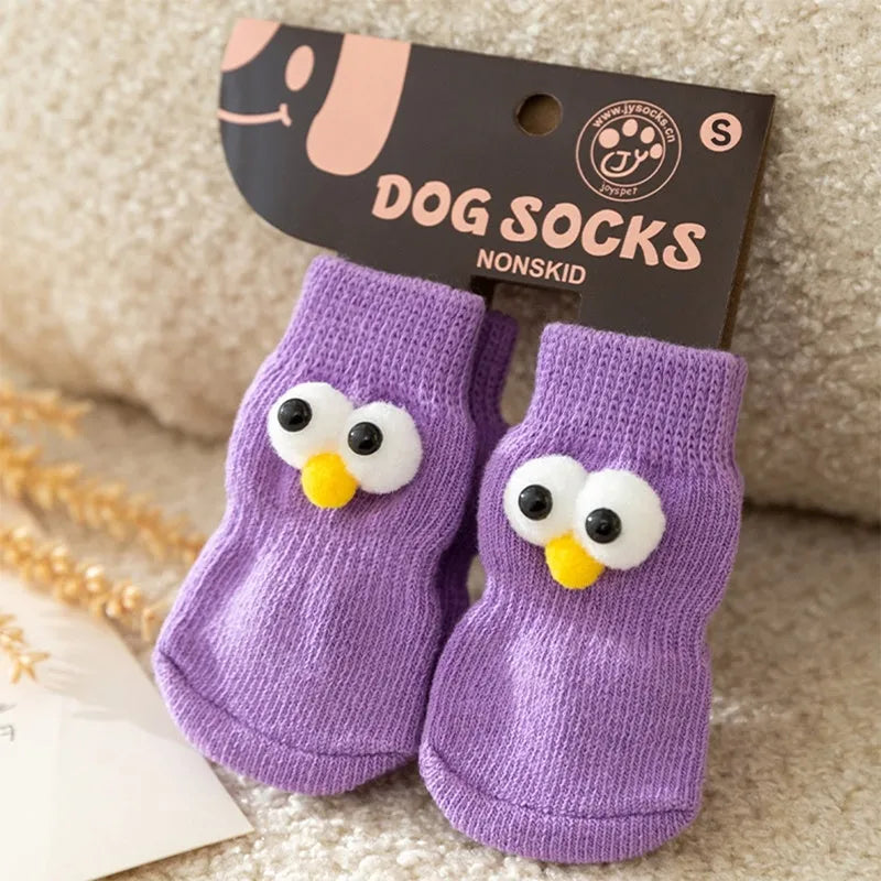Dog wearing green non-slip socks with cartoon big eyes pattern on wooden floor