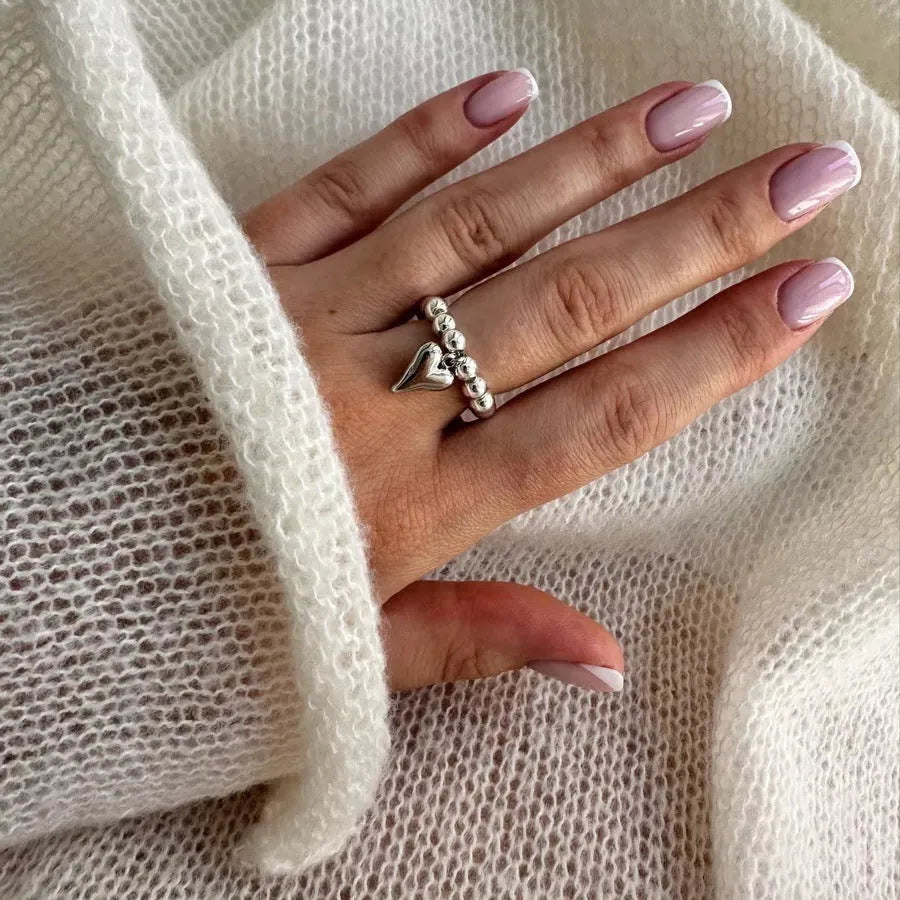 Handmade elastic love ring with geometric beaded string design and heart charm on adjustable band