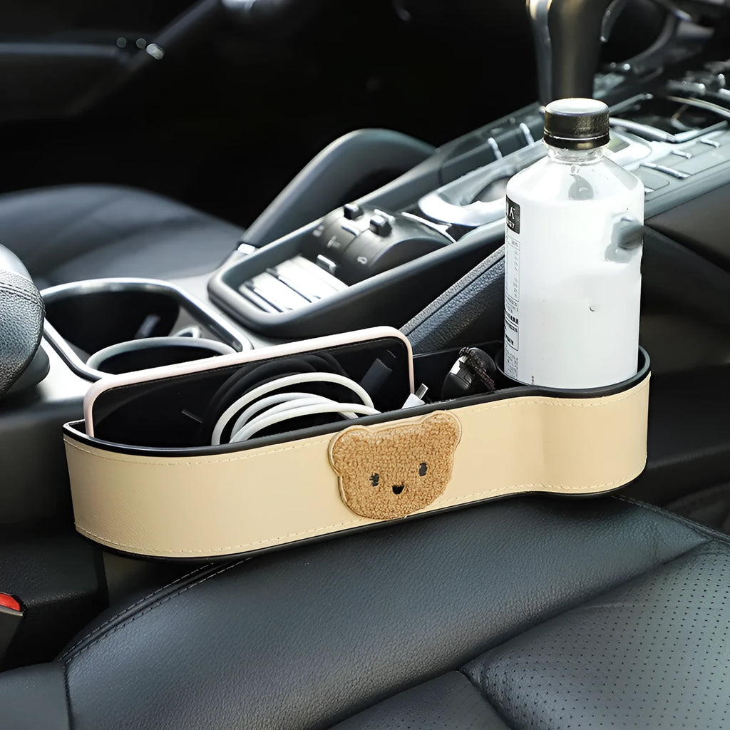 Leather car seat gap storage box with a cartoon bear design, shown hanging between vehicle seats.
