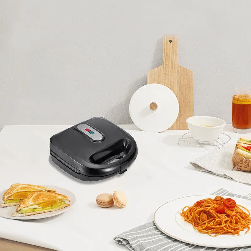 Black double-sided electric sandwich pan with brushed stainless steel lid on kitchen counter