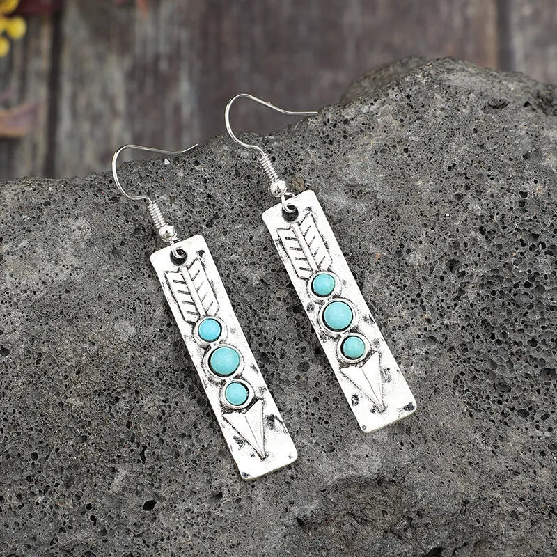 Silver geometric long strip earrings with inlaid turquoise details on a white background.