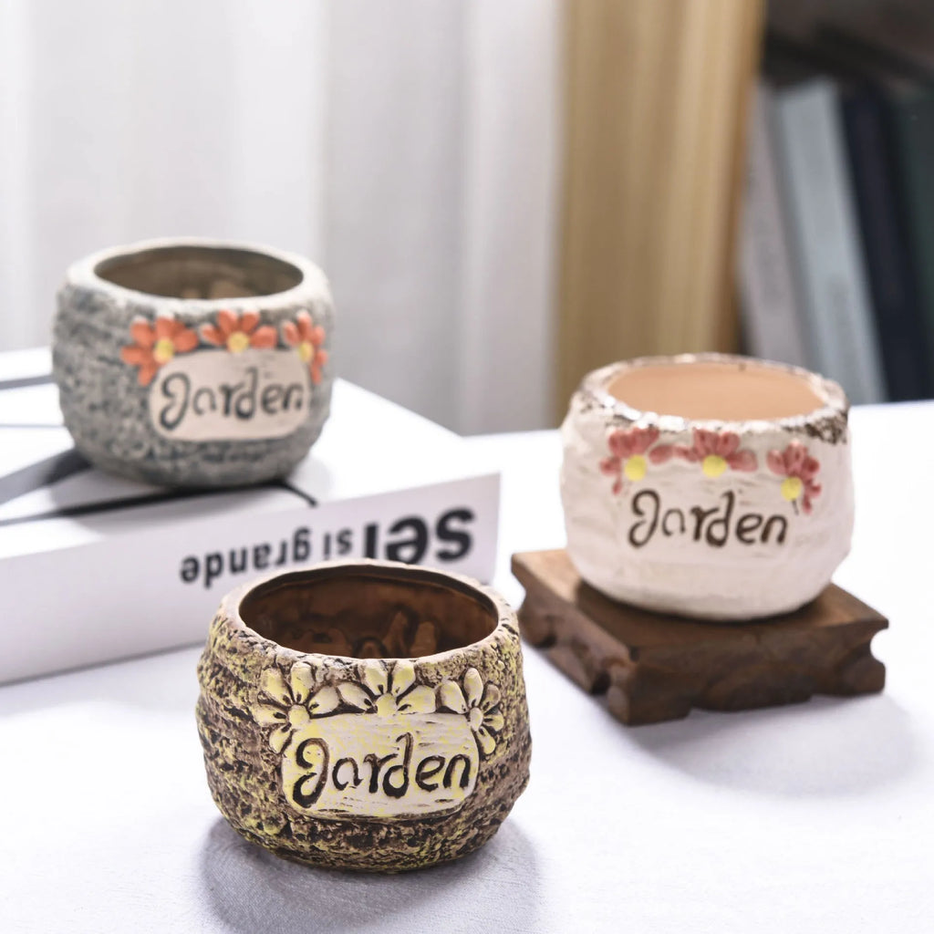 Three breathable stoneware succulent flower pots in hand-painted glaze colours on a tabletop with small succulents inside