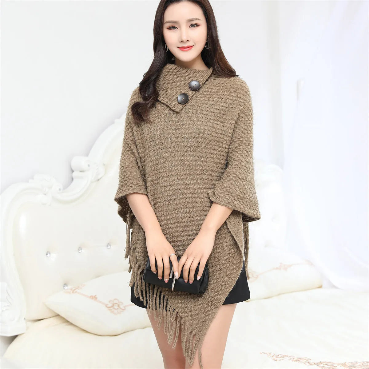 Sleeveless knitted cloak shawl with dot pattern, shown in apricot colour