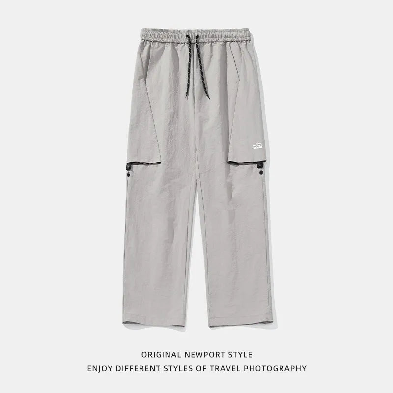 Men's loose-fit nylon casual trousers in black, grey green, or greige, with adjustable split and breathable fabric.