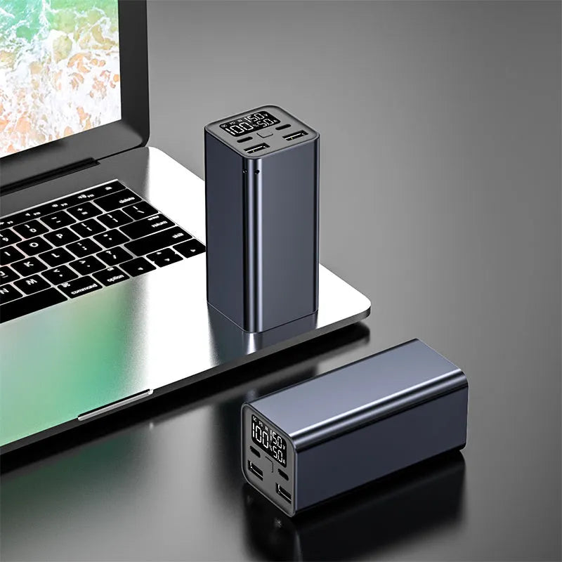 65W metal laptop power bank in black, blue, or grey colours showing size next to a laptop.