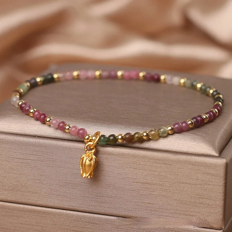 Natural tourmaline beaded anklet with a floral charm, shown being worn.