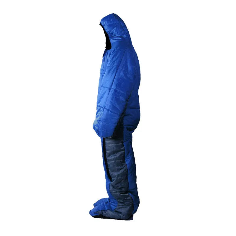 Blue gray patchwork humanoid sleeping bag on grass, legs separated for walking, mummy hood zipped with fill visible.