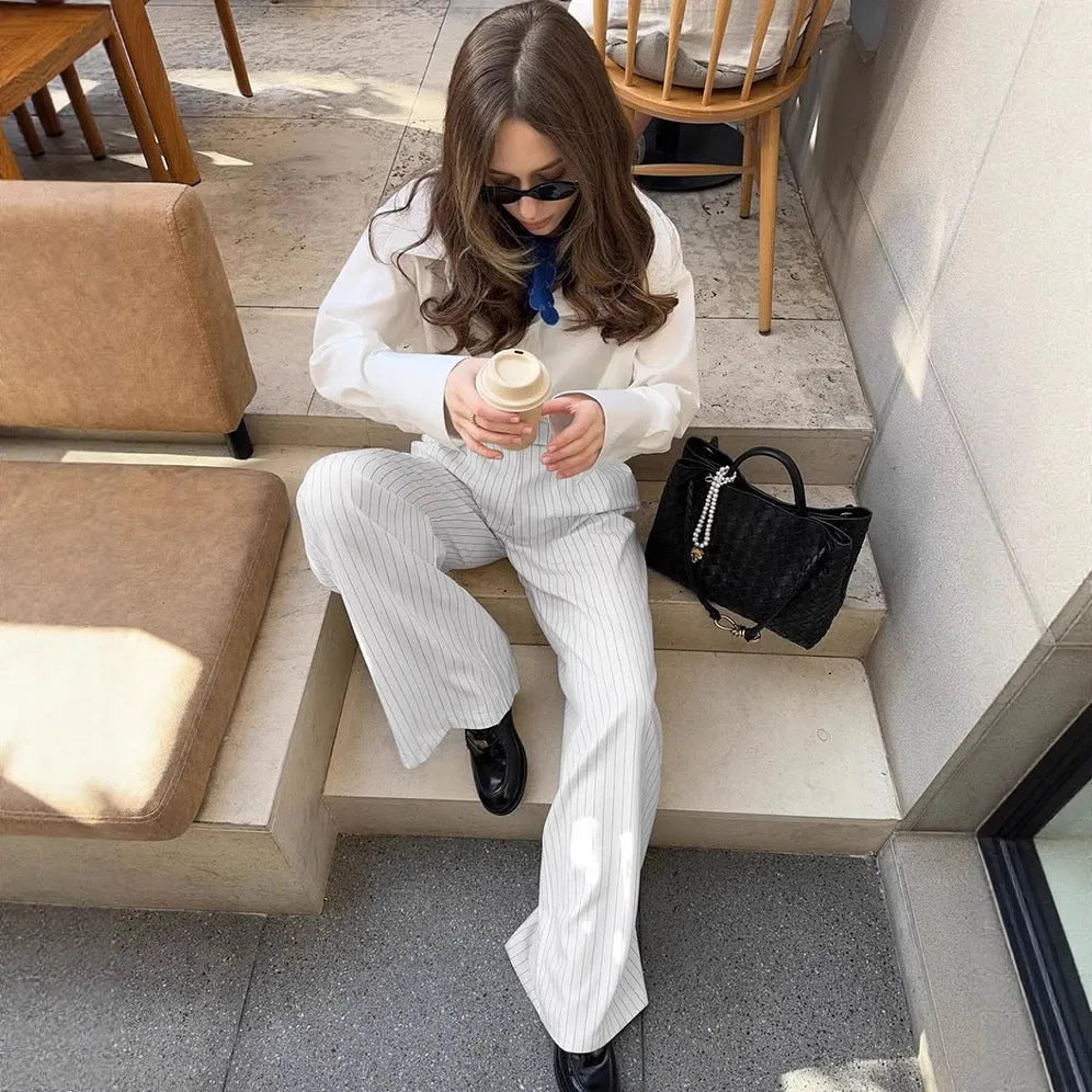 White striped loose-fit wide-leg trousers with a front zipper closure on a model.