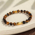 Close-up of a yellow tiger eye beaded bracelet with a detailed small fish charm.