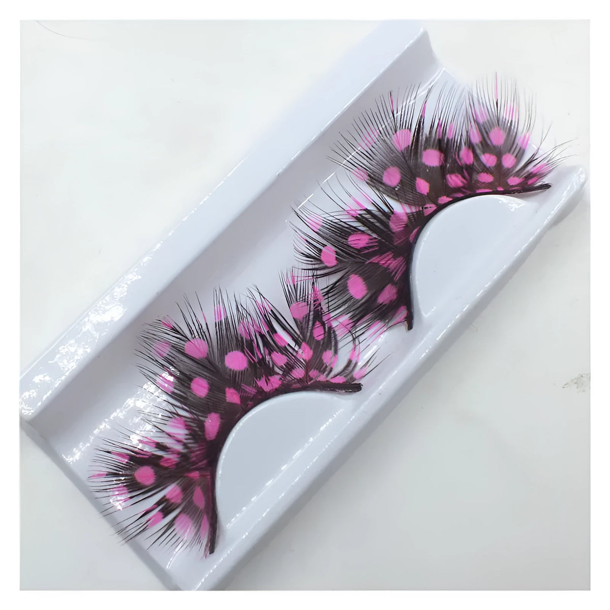 Handmade two-tone feather false eyelashes on a flat surface showing colour matching and feather texture