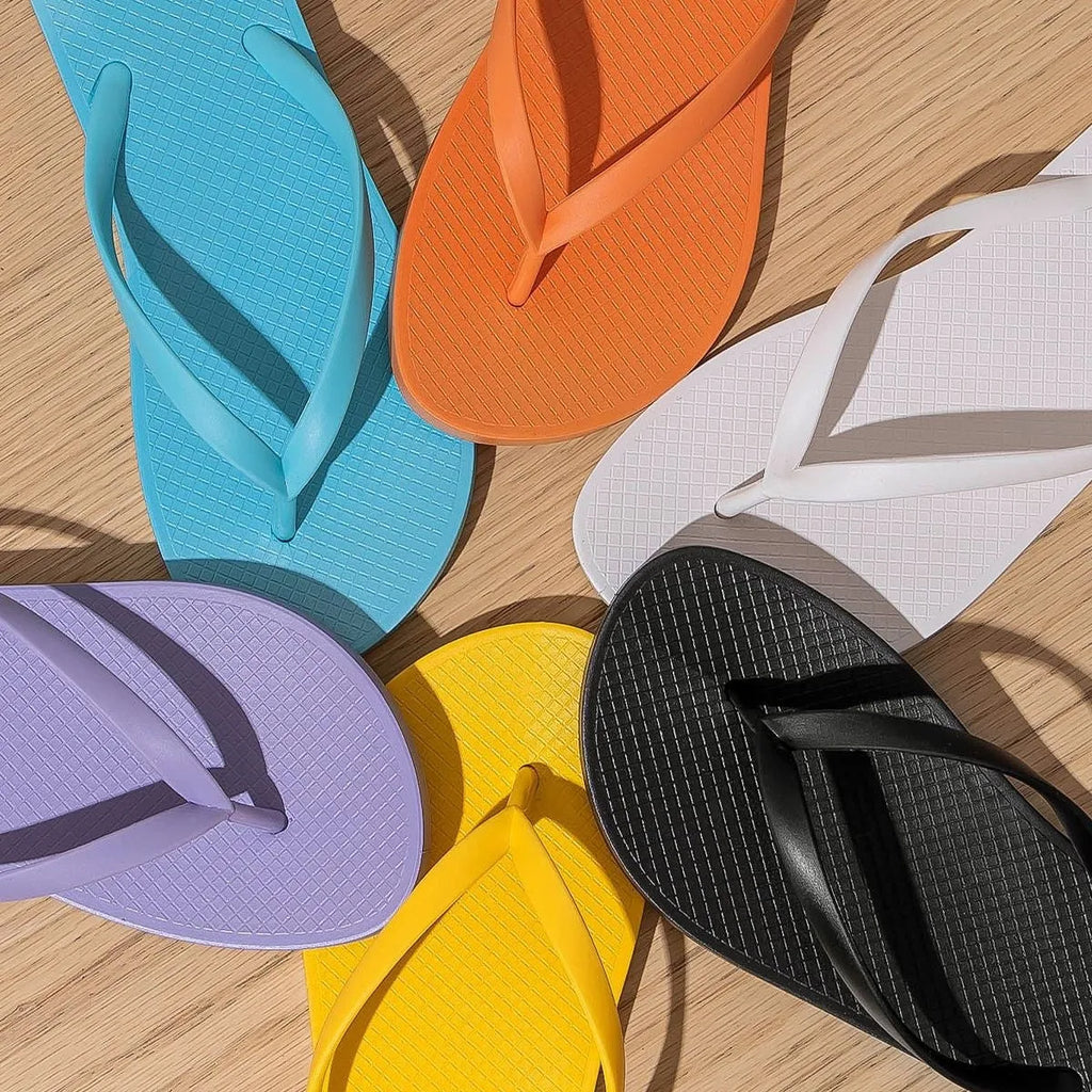 Orange and black flat beach slippers with hollow-out plastic uppers and textured non-slip PVC soles.
