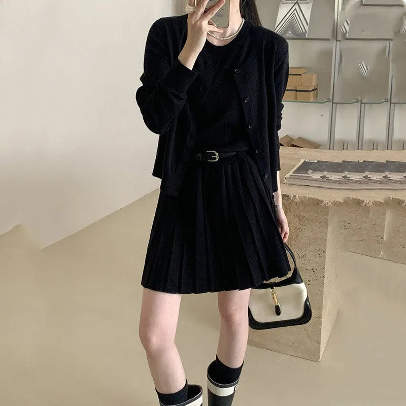 Women's black knitted vest skirt and long-sleeved cardigan two-piece set with pleats and a belt.