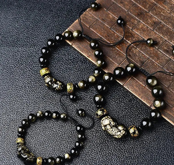 Golden obsidian bead Pi Xiu bracelet with hand-woven design on a wrist.
