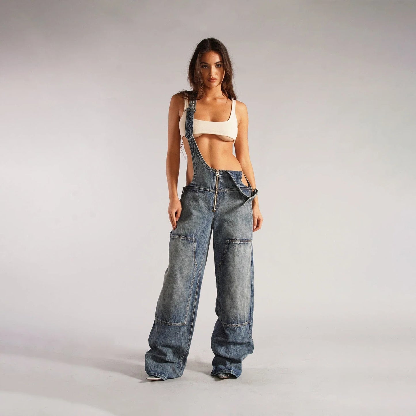 Stylish Y2K-inspired denim suspender jumpsuit with pockets, featuring a relaxed wide-leg silhouette and adjustable straps for a customized fit.