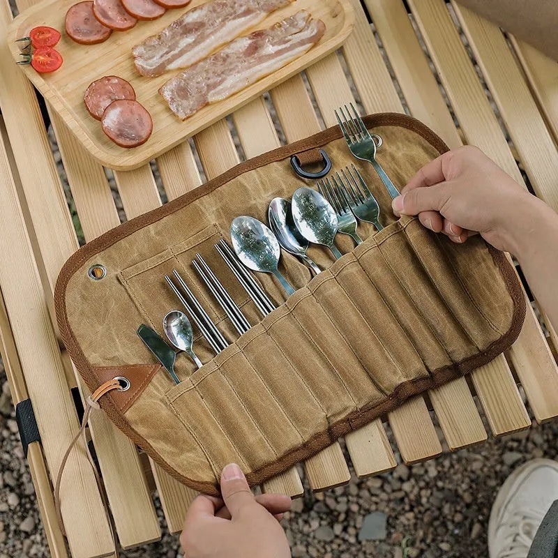 Waxed canvas portable storage bag containing a wooden handle knife, fork, spoon, butter knife, and chopsticks for outdoor dining.