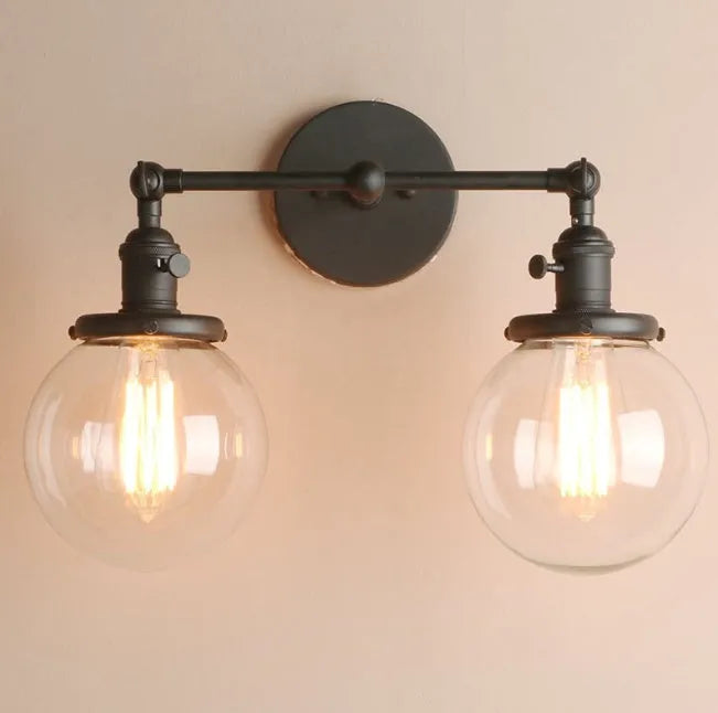 Double headed black iron wall lamp with spherical glass shades on a wall