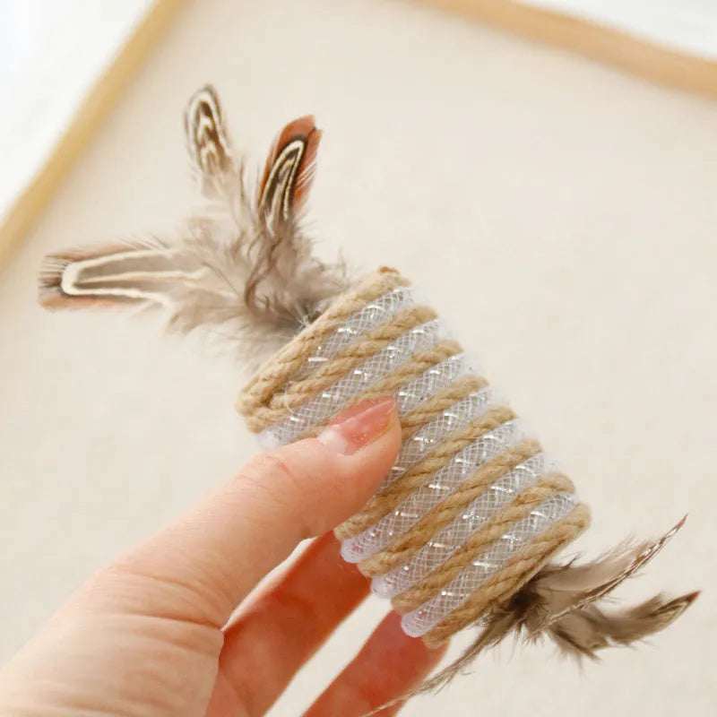 Beige cat toy with hemp rope scratching post, feathers, and a built-in sound roller on a neutral background.