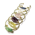 Rough natural crystal bracelet with gold winding geometric design on a wrist.