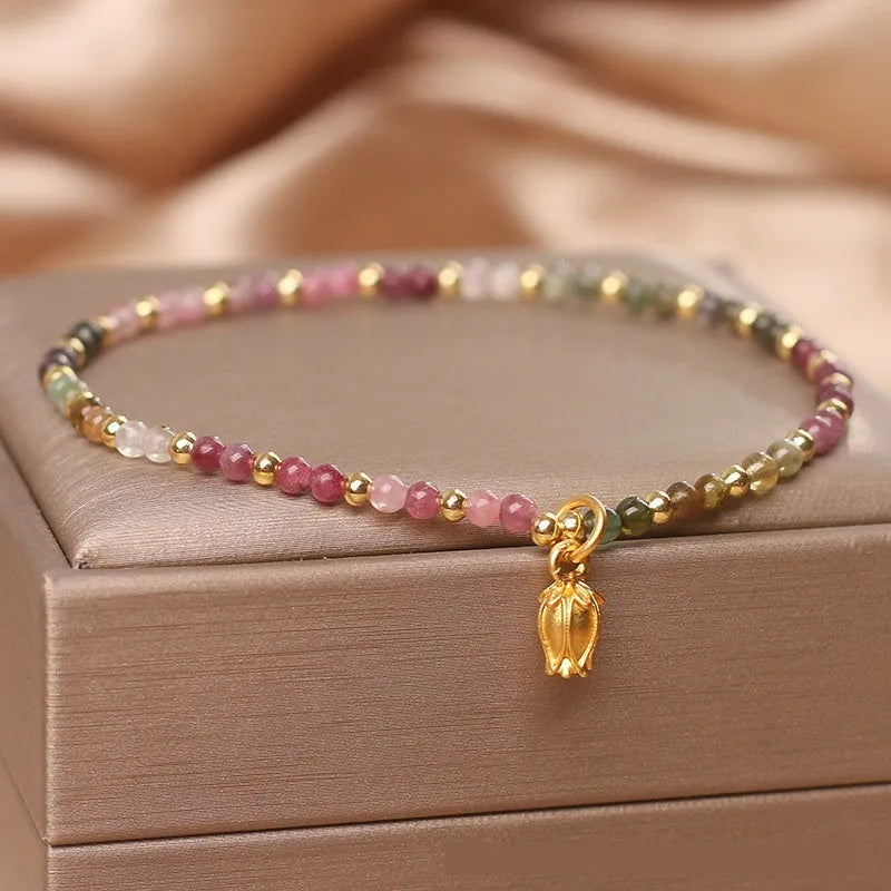 Natural tourmaline beaded anklet with a floral charm, shown being worn.