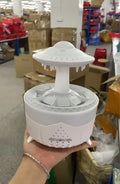 White cloud-shaped UFO raindrop humidifier diffuser with coloured night light on a wooden table.