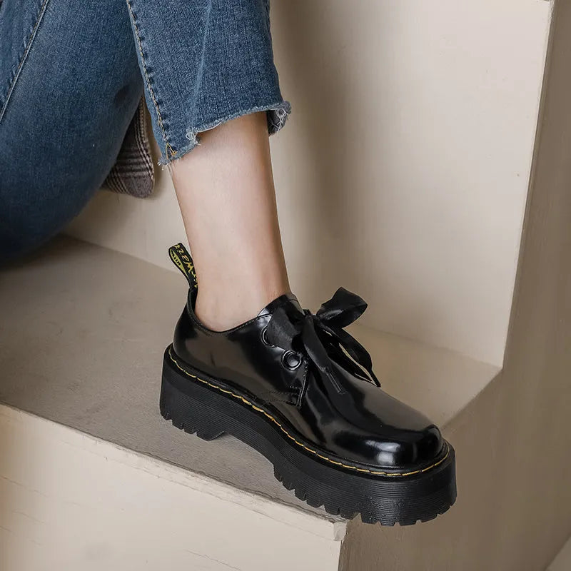 Black and white women's thick-soled small leather shoes with lace-up closure, ribbons, and cross straps.