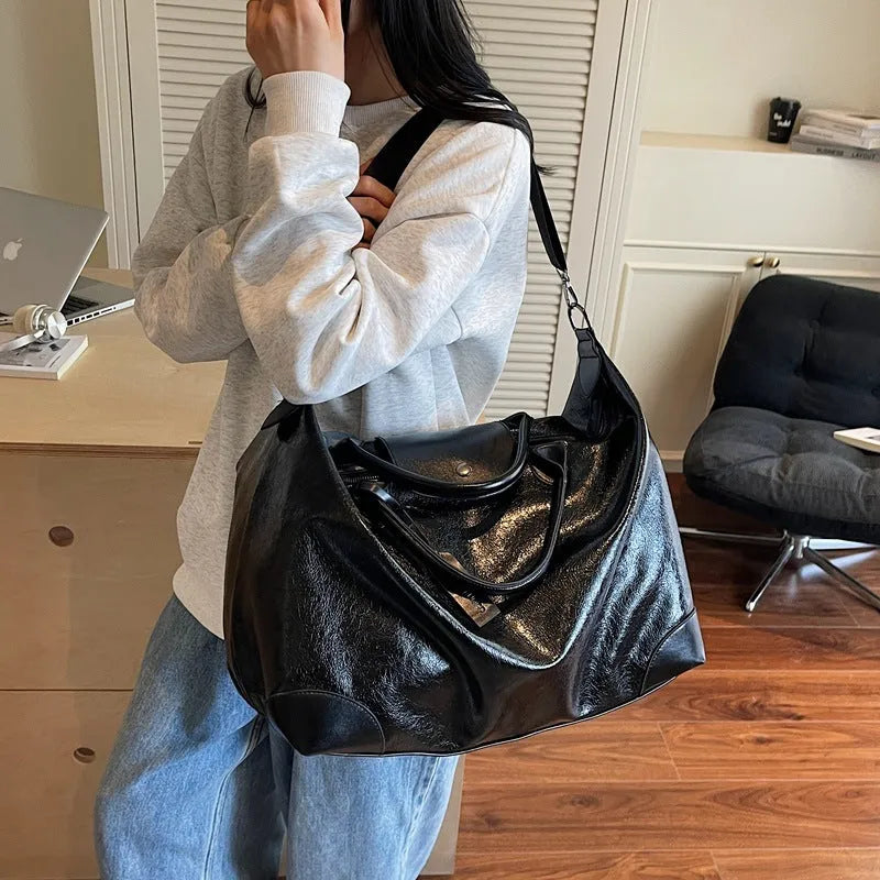 Women's large capacity hand-carry travel bag in black or silver colours with 36-55 litre volume