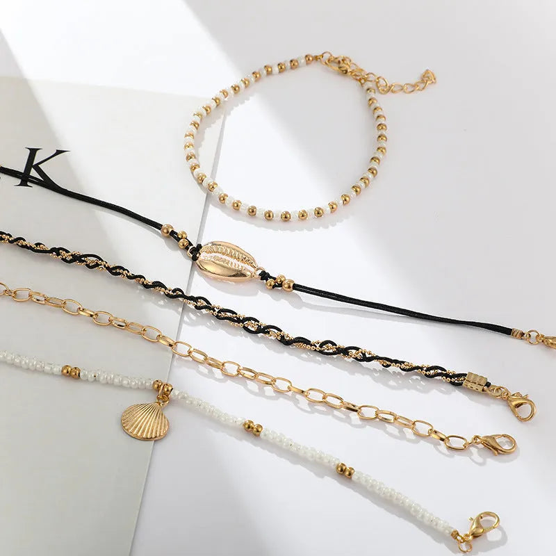 Five-piece gold tone anklet set with braided, shell and geometric ethnic style anklets for women