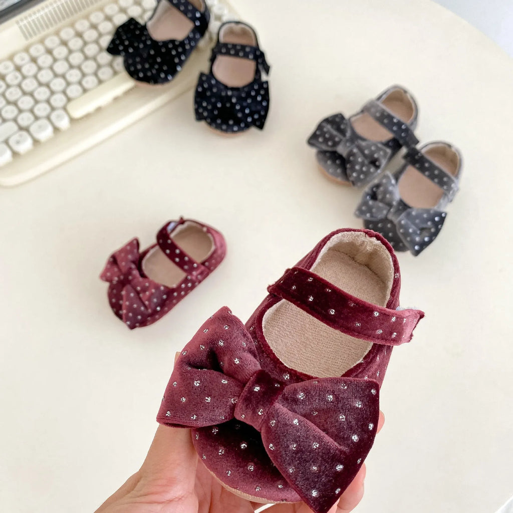 Baby girl toddler shoes with big bow and dots pattern in black on white background