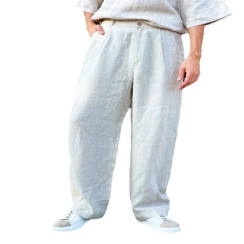 Man wearing loose grey linen-cotton jogger pants with pleated front, high waist, and straight leg.
