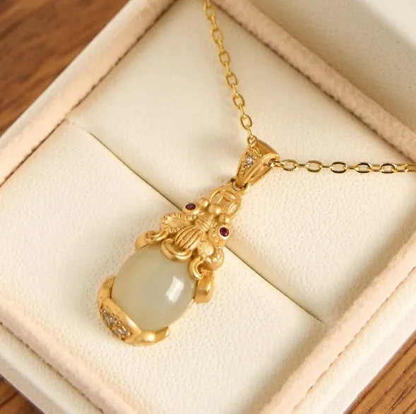 Cartoon character Hetian white jade antique gold pendant necklace with emerald pixiu charm on a chain.
