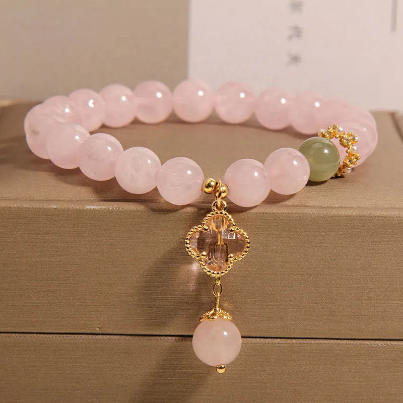 Pink crystal women's bracelet with a four-leaf clover pendant and sparkling rhinestone details.