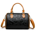 Brown cylindrical leather-effect crossbody bag with three shoulder straps on a table.