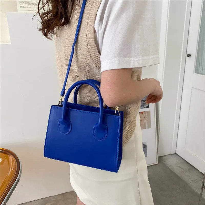 Small square shoulder bag in PU leather with single strap and document pocket, shown in available colours