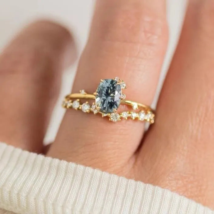 Close-up of a gold-plated floral ring with a central green zircon stone on a model's hand.