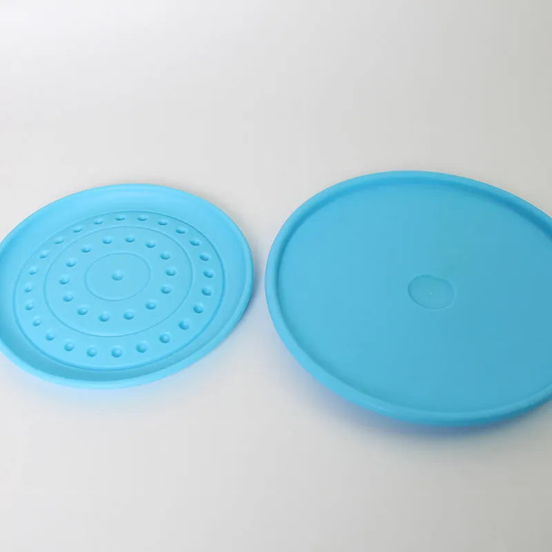 Plastic dog frisbee toy in green, shown on grass for fetch play.