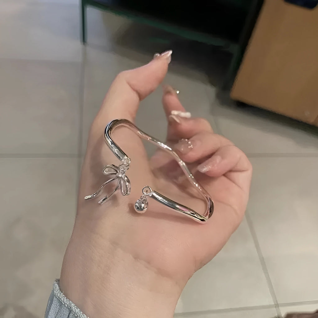 Silver-coloured adjustable bracelet for women featuring a bow charm and a sliding clasp.