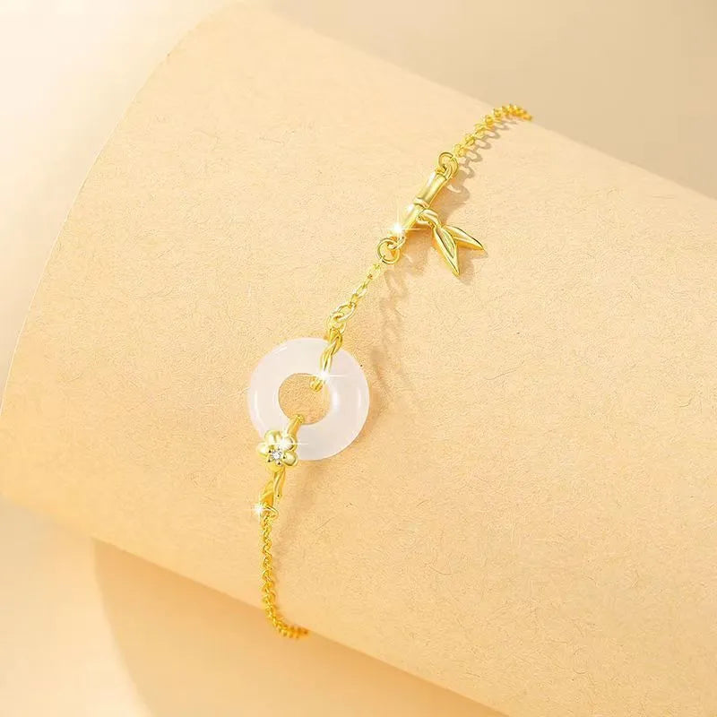 Gold tone women's bracelet with white chalcedony stone and adjustable peace symbol buckle closure